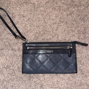 A grey navy blue coach wristlet. In fair condition. Does need a good cleaning.